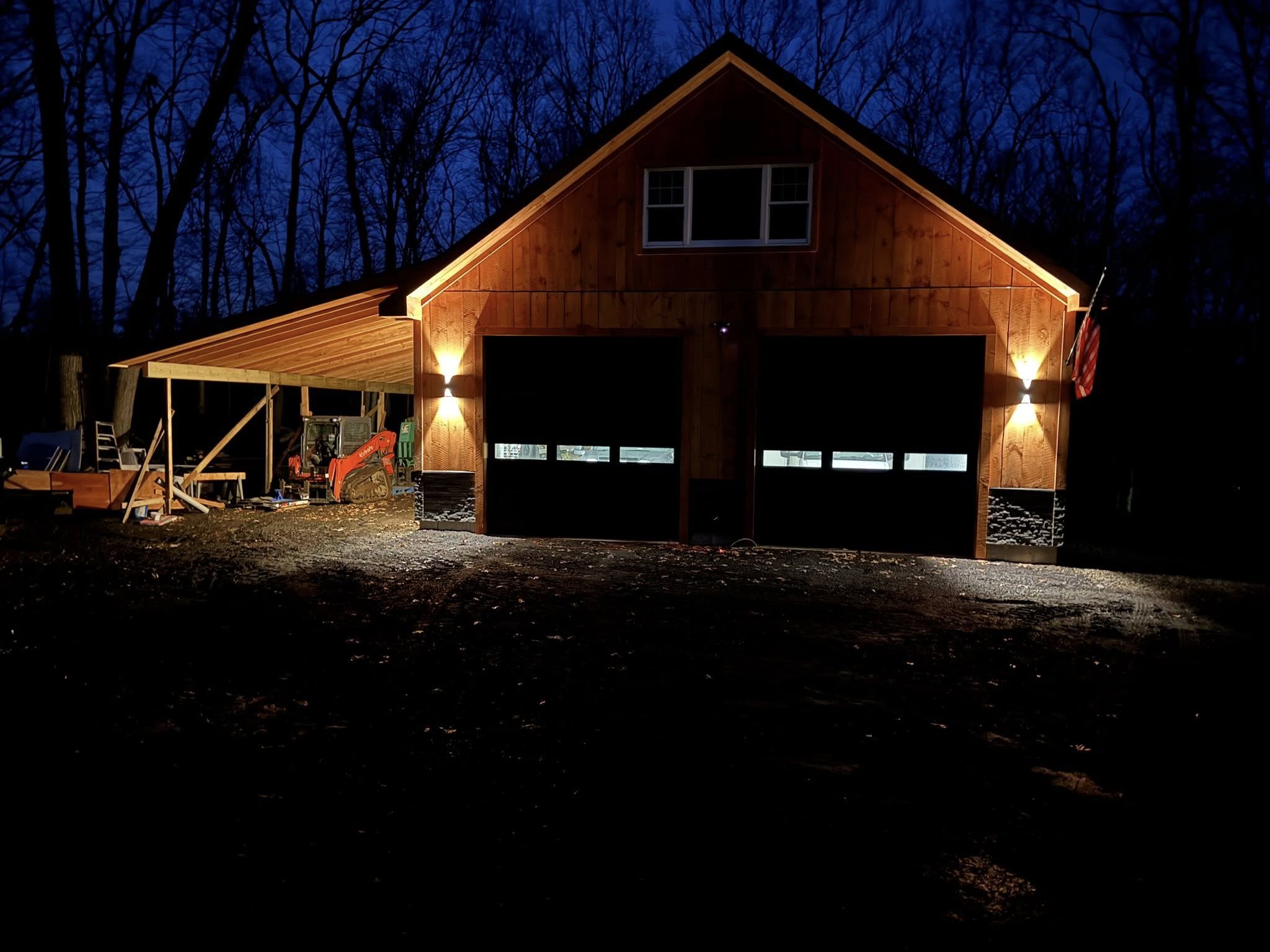 Custom detached garage with dual bays and side workshop built by Lagace Construction in Connecticut, illuminated at night.
